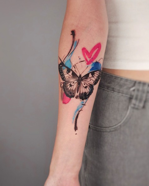 Watercolour butterfly tattoo with a pink heart by Klaudia at Silent Moon, our private tattoo studio in Bermondsey, South East London.