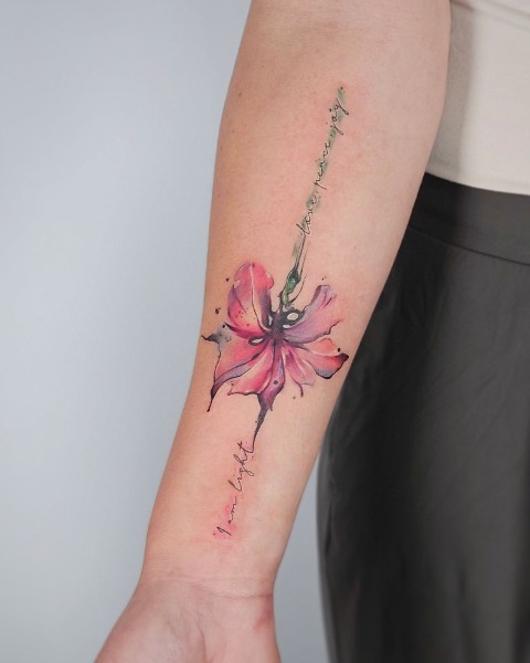 Watercolour pink lily tattoo with fine script by Klaudia at Silent Moon, our private tattoo studio in Bermondsey, South East London.