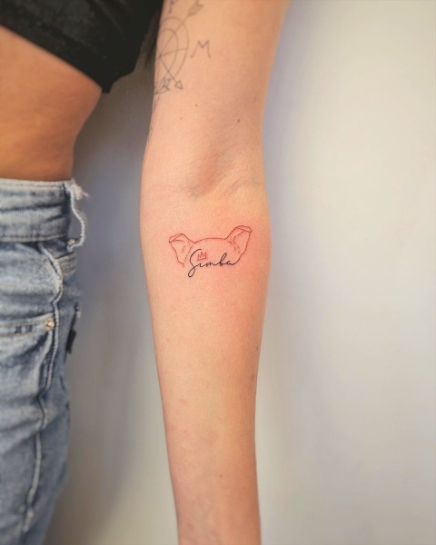 Fine line red ink dog ear tattoo with a pet's name by Klaudia at Silent Moon, our private tattoo studio in Bermondsey, South East London.