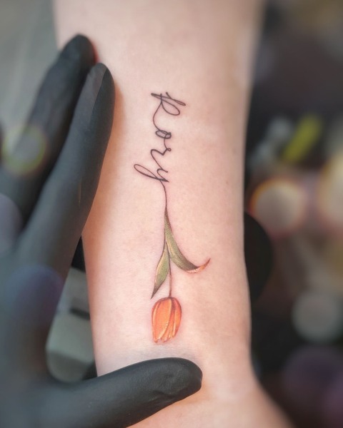 Fine line handwritten name and orange tulip tattoo by Klaudia at Silent Moon, our private tattoo studio in Bermondsey, South East London.