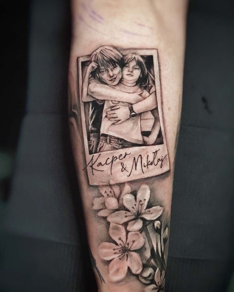 Polaroid frame children's portrait tattoo with fine line script by Klaudia at Silent Moon, our private tattoo studio in Bermondsey, South East London.