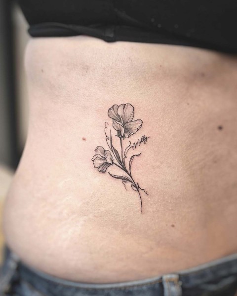 Fine line sweet pea flower tattoo with a script name by Klaudia at Silent Moon, our private tattoo studio in Bermondsey, South East London.