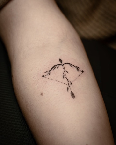 Fine line bow and arrow tattoo with leafy branches by Klaudia at Silent Moon, our private tattoo studio in Bermondsey, South East London.