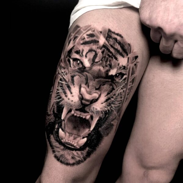 High-contrast black and grey realism roaring tiger portrait tattoo on the thigh, featuring intense detail in the fur and mouth with abstract graphic elements. Custom wildlife realism piece tattooed at Silent Moon Tattoo Studio in London.