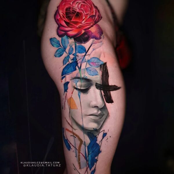 Abstract Realism Red Rose & Portrait Tattoo | Vibrant Thigh Art London High-impact abstract realism tattoo on the thigh featuring a black and grey female portrait, a vibrant red realism rose, and abstract blue/black brushstrokes. Custom conceptual colour piece tattooed at Silent Moon Tattoo Studio in London.