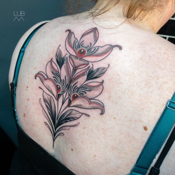 Illustrative floral tattoo on the back/shoulder blade featuring flowers with realistic eyes in their centers, executed in blackwork shading with red and pink accents. Custom dark art tattooed at Silent Moon Tattoo Studio London UK.