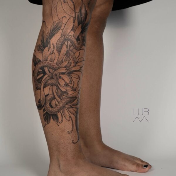 Black and grey snake leg tattoo with floral design by tattoo artist at Silent Moon Tattoo Studio in London.