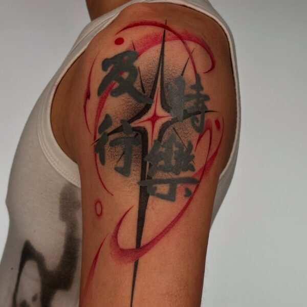 Abstract blackwork Japanese kanji tattoo meaning "Carpe Diem" (Seize the Day) with a red brushstroke background and abstract graphic elements on the shoulder. Custom Asian script tattooed at Silent Moon Tattoo Studio London UK