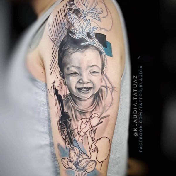 Abstract Realism Child Portrait Tattoo | Sketch Lines & Flowers | Silent Moon London Abstract realism child portrait tattoo on upper arm with sketch line flowers and blue graphic accents. Memorial portrait tattooed at Silent Moon Tattoo Studio London UK.