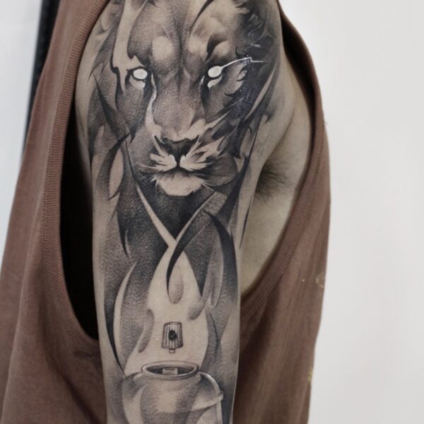 Abstract realism lion portrait tattoo on the half sleeve with abstract flames and a spray paint can. Black and grey custom art tattooed at Silent Moon Tattoo Studio London UK.