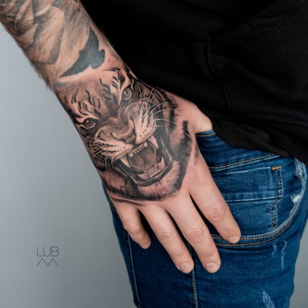 Realistic roaring tiger hand tattoo in black and grey by tattoo artist at Silent Moon Tattoo Studio in London.