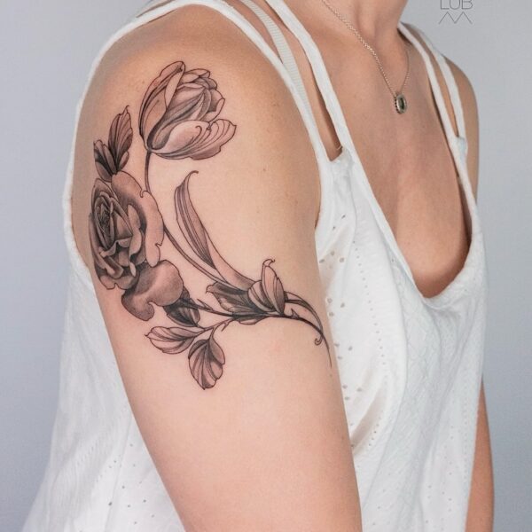 Black and grey floral tattoo with roses and tulips on upper arm by tattoo artist at Silent Moon Tattoo Studio in London.