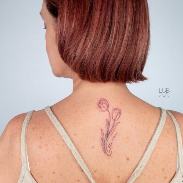 Fine line tulip tattoo with name script on upper back by tattoo artist at Silent Moon Tattoo Studio in London