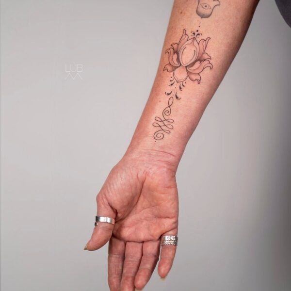 Minimalist lotus flower and hamsa forearm tattoo by tattoo artist at Silent Moon Tattoo Studio in London