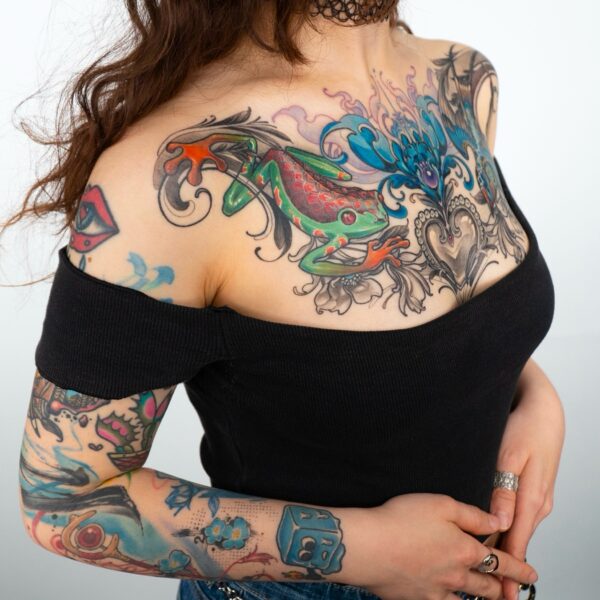 Colourful chest tattoo with green frog and ornamental blue and black design by tattoo artist at Silent Moon Tattoo Studio in London